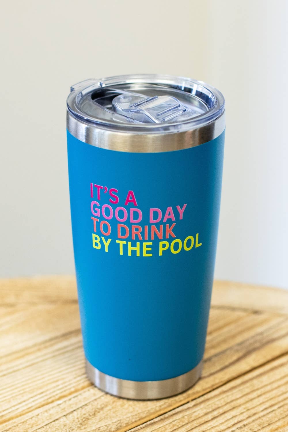 Blue tumbler with colorful text on a wooden surface